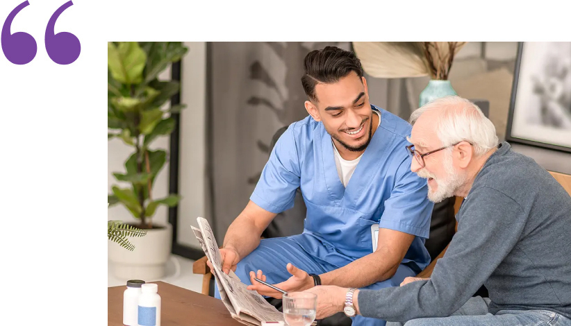 Old man in eyeglasses patting his smiling cheerful Caucasian in-home male caregiver on the shoulder